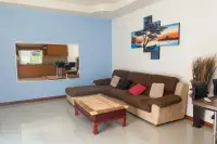 2 Bedroom House for Rent living area with a brown sectional sofa, coffee table, and colorful wall art.