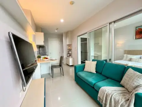 1 Bedroom Condo for Sale at Centric Sea open-plan living area with teal sofa, dining nook, and bedroom view
