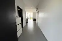 3 Bedroom House for Sale at The Prestige at Siam Royal View: Long hallway with white walls and gray tiled floor leading to the living area.
