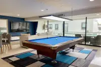 1 Bedroom Condo for Sale at Gardenia Pattaya billiards room with blue pool table, pendant light, white sofa and glass balcony doors