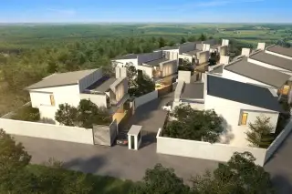 Thamber Private Pool Villa aerial view of modern villas nestled in a green forest, with a gated entrance and road.