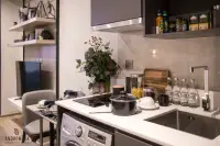 Studio Condo for Sale at Andromeda Condominium compact kitchen with induction hob, stainless steel sink, washing machine, and open shelving