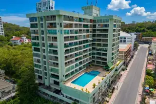 Sombat Pattaya Condotel: Aerial view of the light green building with a rooftop swimming pool and surrounding city street.