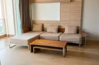 2 Bedroom Condo for Sale at Cetus Beachfront living room with modern sectional sofa, wood coffee table and wood panel wall