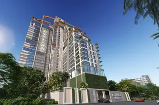 The Riviera Malibu condo building exterior from street level, showing lush landscaping and a clear blue sky.