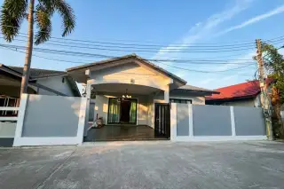 SP Village 1 single-storey house exterior with white and grey walls, gated entrance, and palm tree in Pattaya