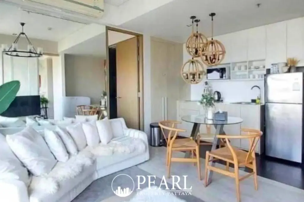 2 Bedroom Condo for Sale at Veranda Residence Pattaya living room with white sofa, dining table, and compact kitchen.