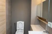 1 Bedroom Condo for Rent at Cetus Beachfront modern bathroom with grey tiles, toilet, vanity sink, and mirrored cabinet