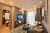 2 Bedroom Condo for Sale at Aquarous Jomtien Pattaya living room with wall-mounted TV, sofa, and balcony door with city view