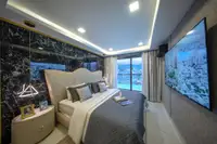 2 Bedroom Condo for Sale at Grand Solaire Noble, bedroom with large bed, black marble wall, and city view balcony.