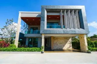 Madcha Nirvana modern house exterior with a grey facade, large windows, and a light orange gate.