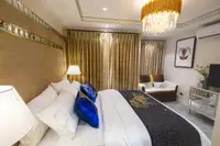 Studio Condo for Sale at Seven Seas Le Carnival: Bedroom with bed, gold curtains, sofa, and open closet with robes.