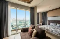 1 Bedroom Condo for Sale at Cetus Beachfront bedroom with double bed, sofa and large balcony overlooking Pattaya city skyline
