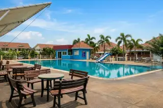 Chokchai Village 8 outdoor swimming pool with blue clubhouse, water slide, and lounge seating under an awning.
