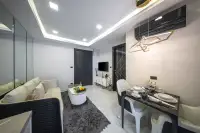 1 Bedroom Condo for Sale at Grand Solaire Noble living and dining area with dark marble-top table, white sofa, and wall-mounted TV