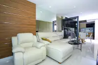 3 Bedroom Condo for Sale at Apus spacious living room with cream leather sectional sofa and wood accent wall