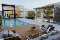 4 Bedroom House for Sale at AVANI Pool Villa poolside wood deck with modern outdoor sofa set and illuminated interior at twilight