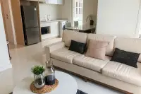 2 Bedroom Condo for Sale at Del Mare open-plan living area with cream sofa, coffee table, and fully equipped kitchen with stainless fridge