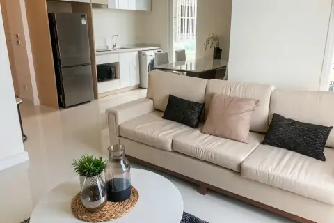 2 Bedroom Condo for Sale at Del Mare open-plan living area with cream sofa, coffee table, and fully equipped kitchen with stainless fridge