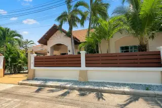 Mike Orchid Villas 2 house exterior with a modern fence, palm trees, and a tiled roof under a sunny sky.