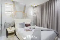 1 Bedroom Condo for Sale at Grand Solaire Pattaya: Bedroom with large bed, marble accent wall, and decorative lighting.