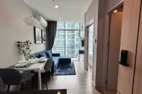 1 Bedroom Condo for Sale at The Twin Tower Jomtien Beach Pattaya open-plan living and dining area with blue sofa and balcony