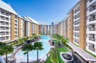 Wyndham Jomtien Pattaya aerial view of the outdoor swimming pool area with multiple pools, palm trees, and buildings.