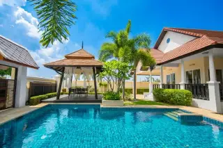 Green Residence Village outdoor swimming pool with a gazebo, palm trees, and a house under a blue sky.