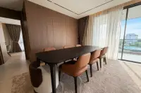 3 Bedroom Condo for Rent at Panora Estuaria formal dining area with large dark table, tan leather chairs, wood-panel wall and floor-to-ceiling windows