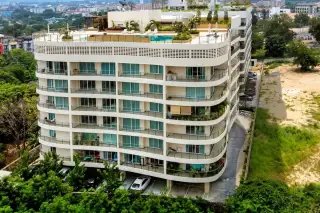 Hyde Park Residence 1 aerial view of the curved condo building with rooftop pool and city skyline.