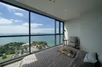 2 Bedroom Condo for Sale at Andromeda Condominium bedroom with floor-to-ceiling windows overlooking turquoise sea and tropical coastline