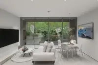 1 Bedroom Condo for Sale at Celine Wongamat bright living room with floor-to-ceiling glass doors opening to lush tropical garden