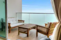 1 Bedroom Condo for Sale at Cetus Beachfront balcony with wooden sofa set, glass railing, and turquoise sea view