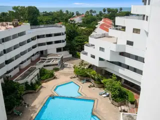 Jomtien Beach Paradise: Rooftop view of residential houses with red roofs, green trees, and distant city skyline.