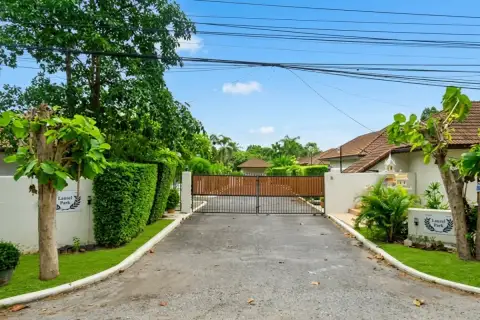 Laurel Park house exterior with tiled roof, driveway, and gated entrance at community sign
