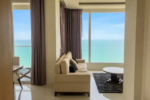 2 Bedroom Condo for Sale at Del Mare spacious living room with cream sofa, dark rug, and dual floor-to-ceiling ocean view windows