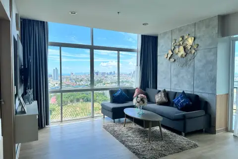 1 Bedroom Condo for Sale at The Twin Tower Jomtien Beach Pattaya furnished living room with L-shaped sofa and floor-to-ceiling city view windows