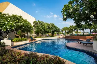 Panchalae Boutique Residence outdoor swimming pool with blue tiles, surrounded by lush tropical plants and white flowering trees.