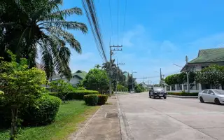 Baan Suan Suwattana Phase 2 entrance gate with security booth and barrier, leading to a residential street.