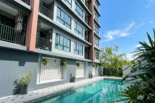 S-Fifty Condominium outdoor swimming pool with patterned paving, a small patio, and lush greenery, viewed from a balcony.