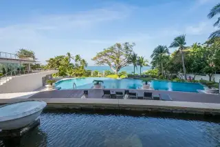 The Cove Pattaya large outdoor swimming pool area with wooden deck, sun loungers, and ocean view.