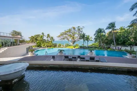 The Cove Pattaya large outdoor swimming pool area with wooden deck, sun loungers, and ocean view.