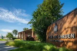 Life in the Garden Rongpo - Motorway modern entrance gatehouse with cars and lush landscaping under a cloudy sky