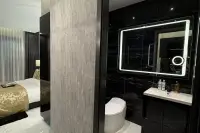 Studio Condo for Sale at Grand Solaire Noble bathroom with black marble tiles, LED-lit mirror, vanity sink, and smart toilet beside bed area