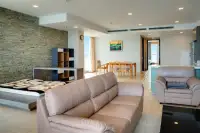 2 Bedroom Condo for Sale at Cetus Beachfront open-plan living and dining area with stone feature wall and sea views