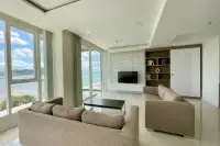 3 Bedroom Condo for Sale at Del Mare spacious living room with beige sofas, TV wall, built-in shelves, and floor-to-ceiling sea views