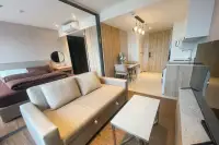 1 Bedroom Condo for Rent at Once Pattaya living space with beige sofa, marble coffee table, bedroom behind glass partition, and compact kitchen