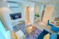 1 Bedroom Condo for Sale at Seven Seas Le Carnival: living room with blue sofa, patterned rug, dining table, and large windows.