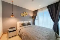 1 Bedroom Condo for Rent at The Riviera Jomtien bedroom with double bed, grey accent wall, gold wall art and floor-to-ceiling window