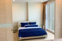 1 Bedroom Condo for Sale at Cetus Beachfront bright bedroom with double bed, blue pillows, wood wardrobe, and large sea-view window